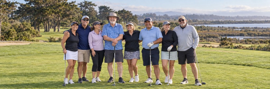 Group of smiling golfers standing together on a sunny fairway at Pajaro Valley Golf Club, with coastal trees and Monterey Slough wetlands in the background.